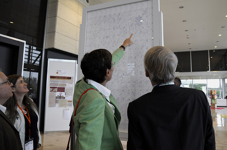 Two people looking at the signatures on the back of a big vertical jigsaw puzzle