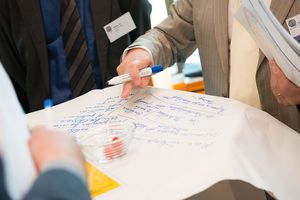 3 people at a cocktail table writing down their thoughts on the tablecloth