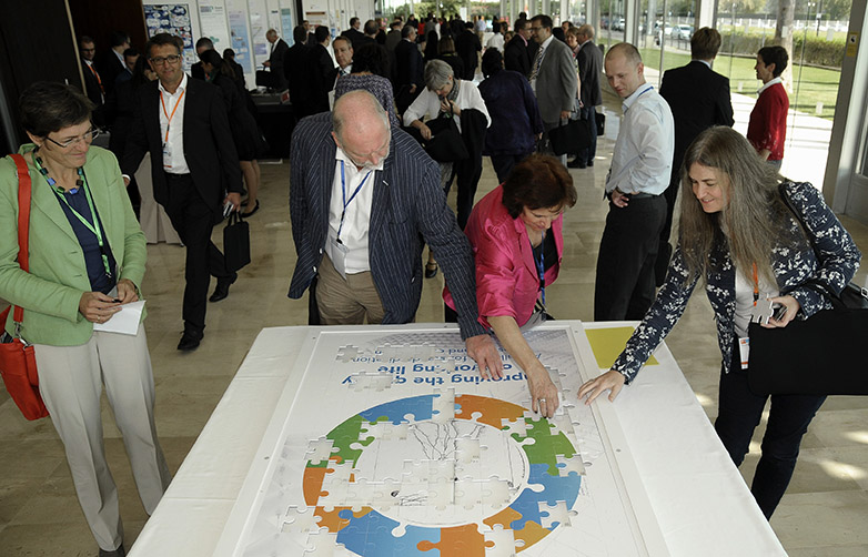People putting a jigsaw piece in a big puzzle showing the conference logo