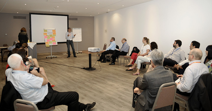 Workshop room with people sitting in circle and listening to a presentation