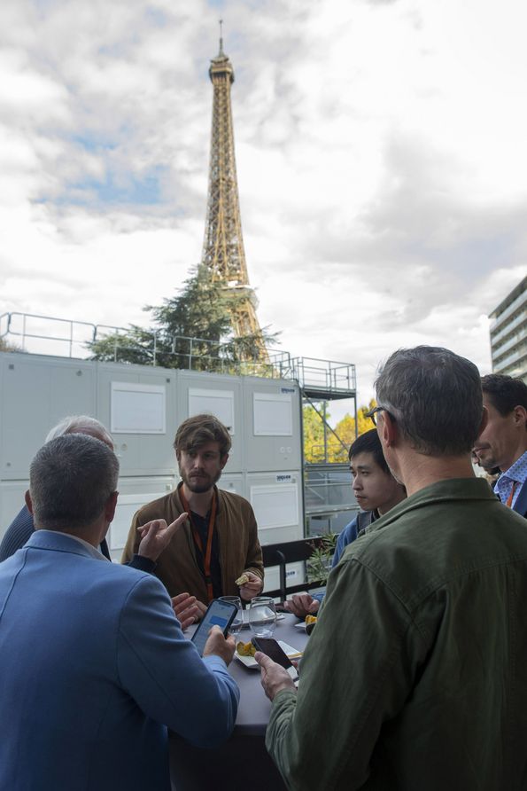 Delegates talking during the lunchbreak on an outdoor terrace with the Eiffel tower in the background